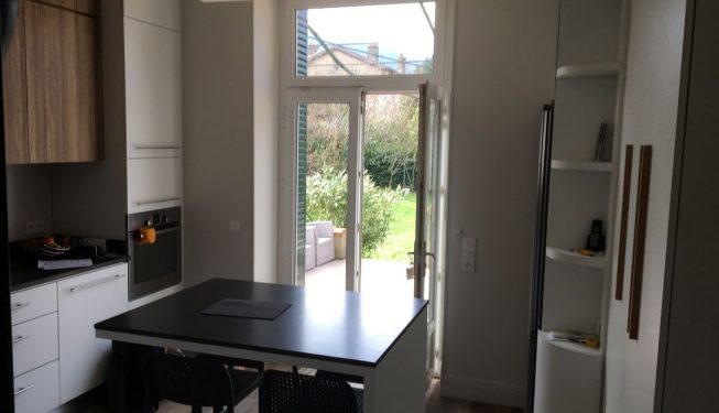 Cuisine Blanche granit noir, porte fenêtre ouverte